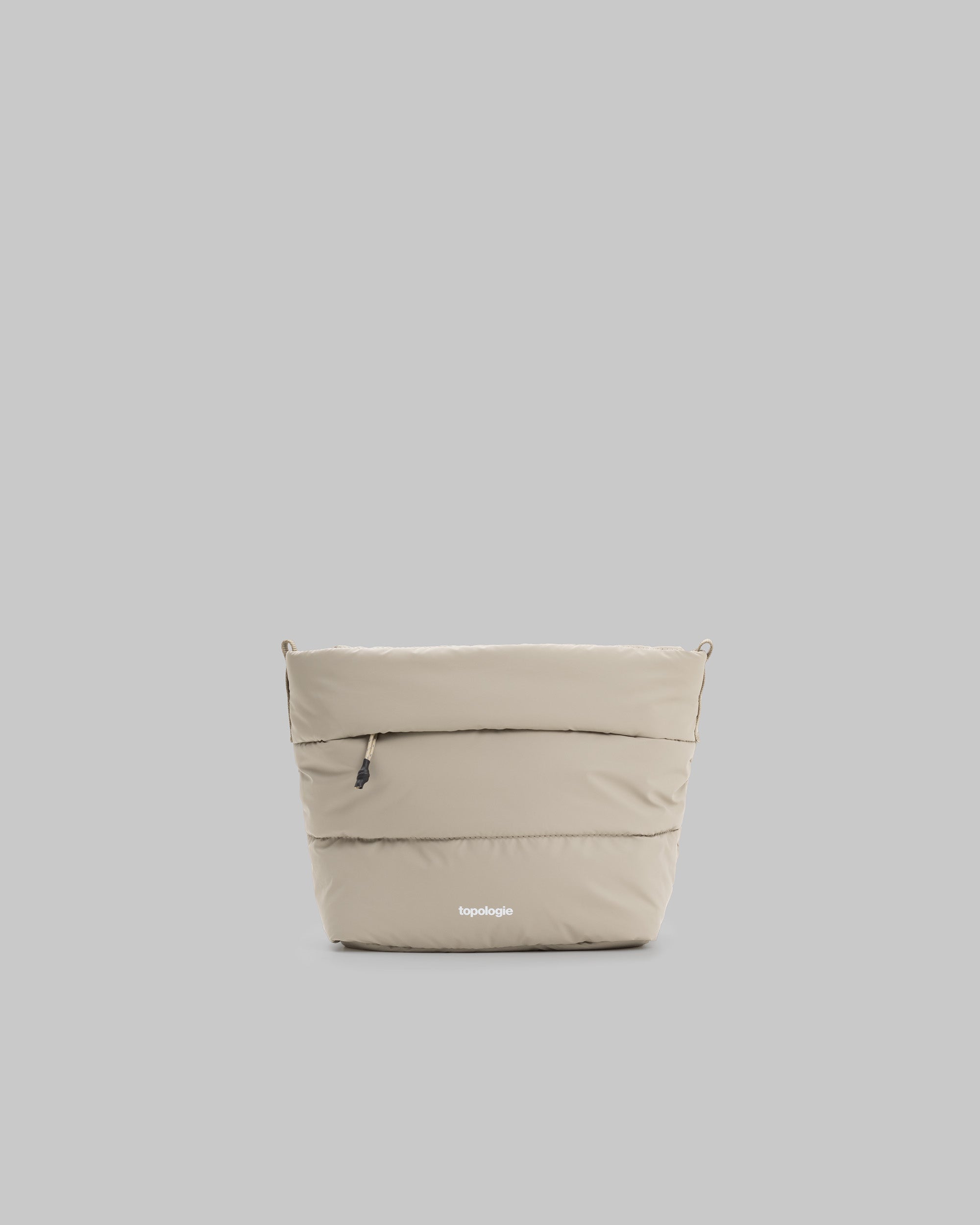 Besace in taupe quilted fabric featuring top attachment loops and a white topologie logo at the base, shown against a light grey background.