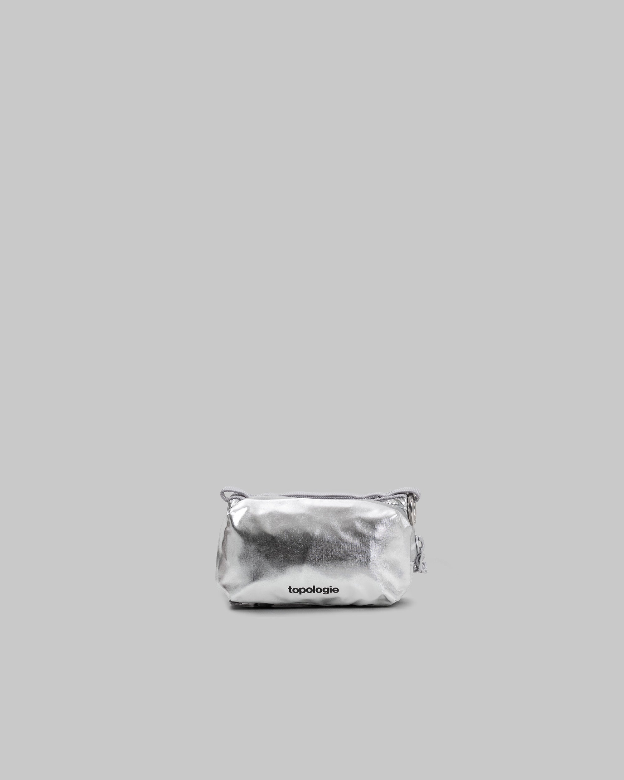 Bottle Sacoche Mini in metallic chrome with a black topologie logo and silver clasp attachment, shown against a light grey background.