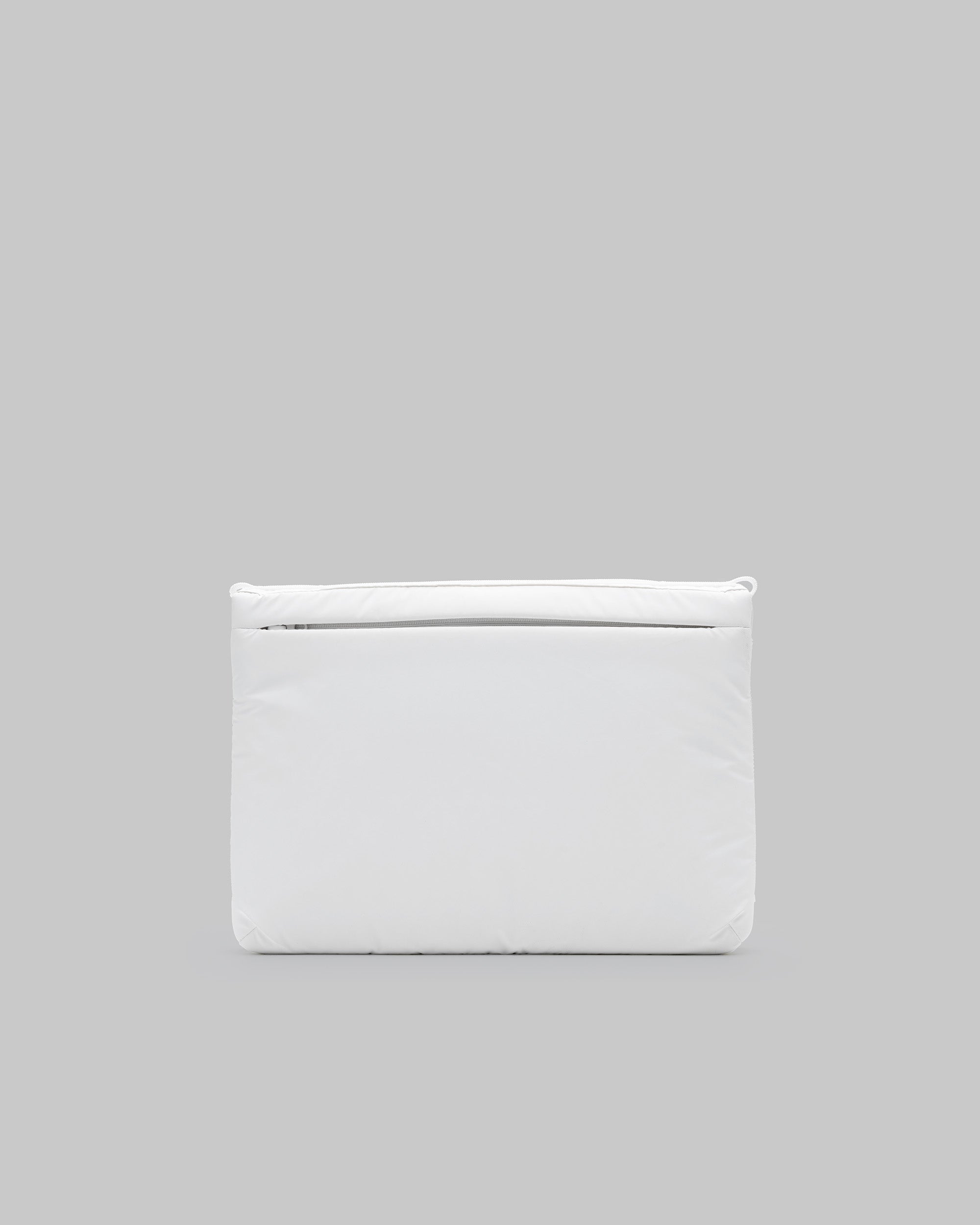 Flat Sacoche Large in white puffy fabric with a horizontal matching zipper and corner loops, shown against a light grey background.
