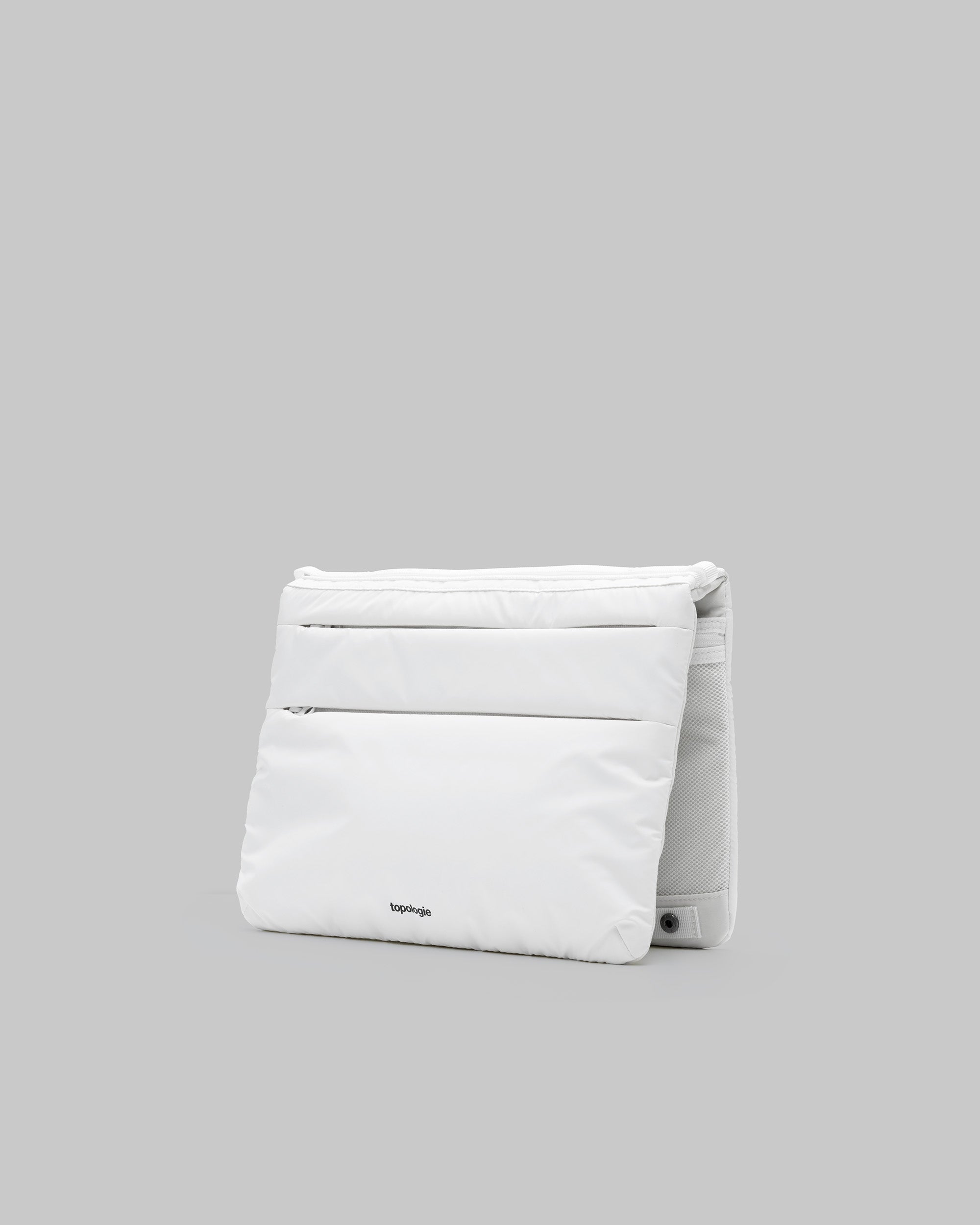 Flat Sacoche Large in white puffy fabric with horizontal quilted zipper pockets and a black topologie logo, shown against a light grey background.