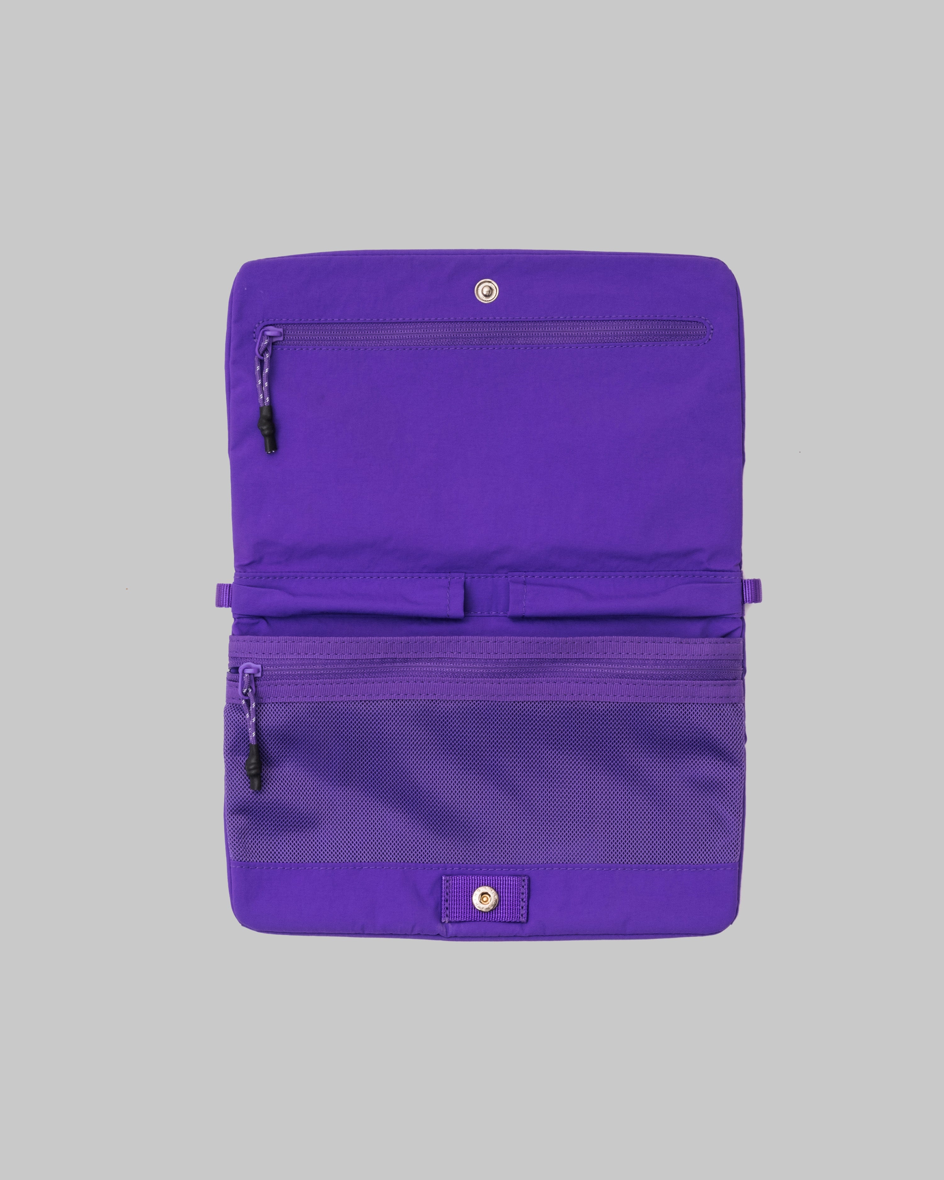 Flat Sacoche Small in bright purple nylon, shown open with zippered compartments, a mesh pocket, and silver snap hardware.