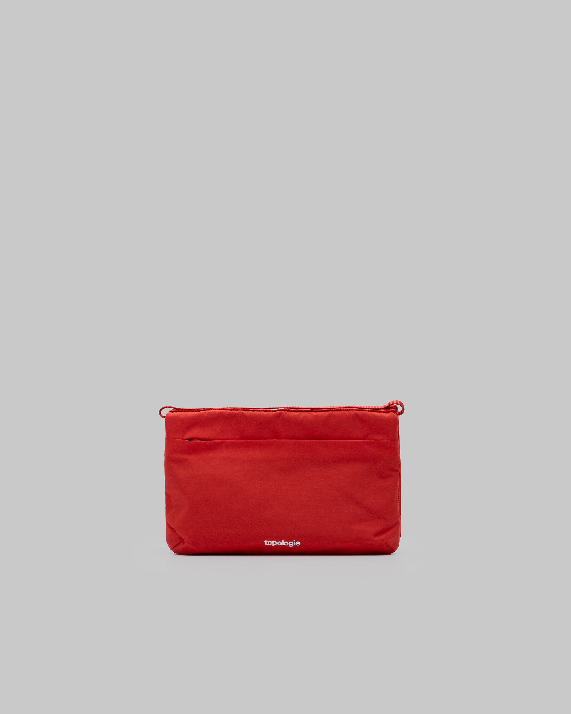 Flat Sacoche Small in bright red matt-coated fabric with a white topologie logo and corner cord loops, shown against a light grey background.