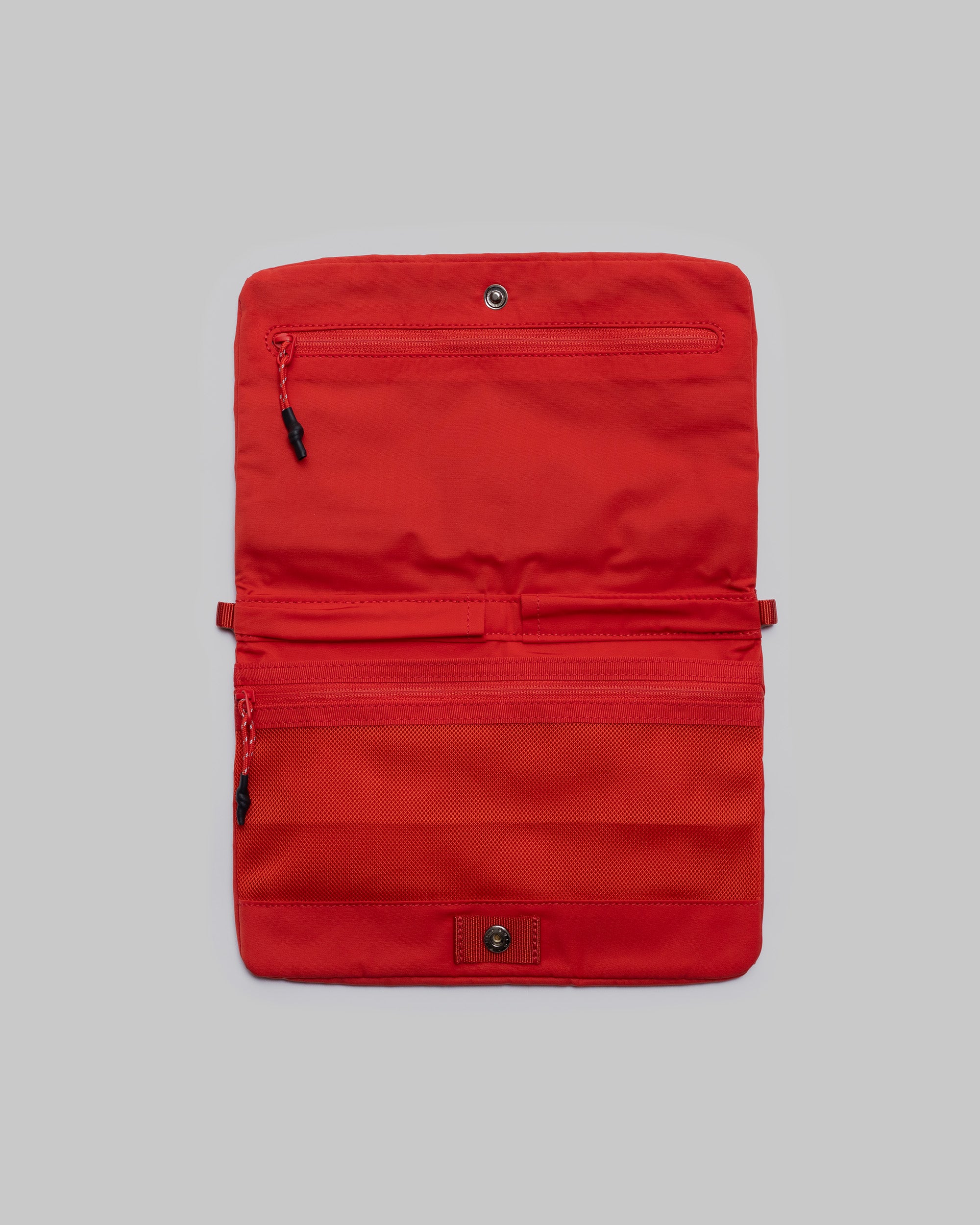 Flat Sacoche Small in red, shown open to reveal zippered mesh compartments and snap closures against a light grey background.