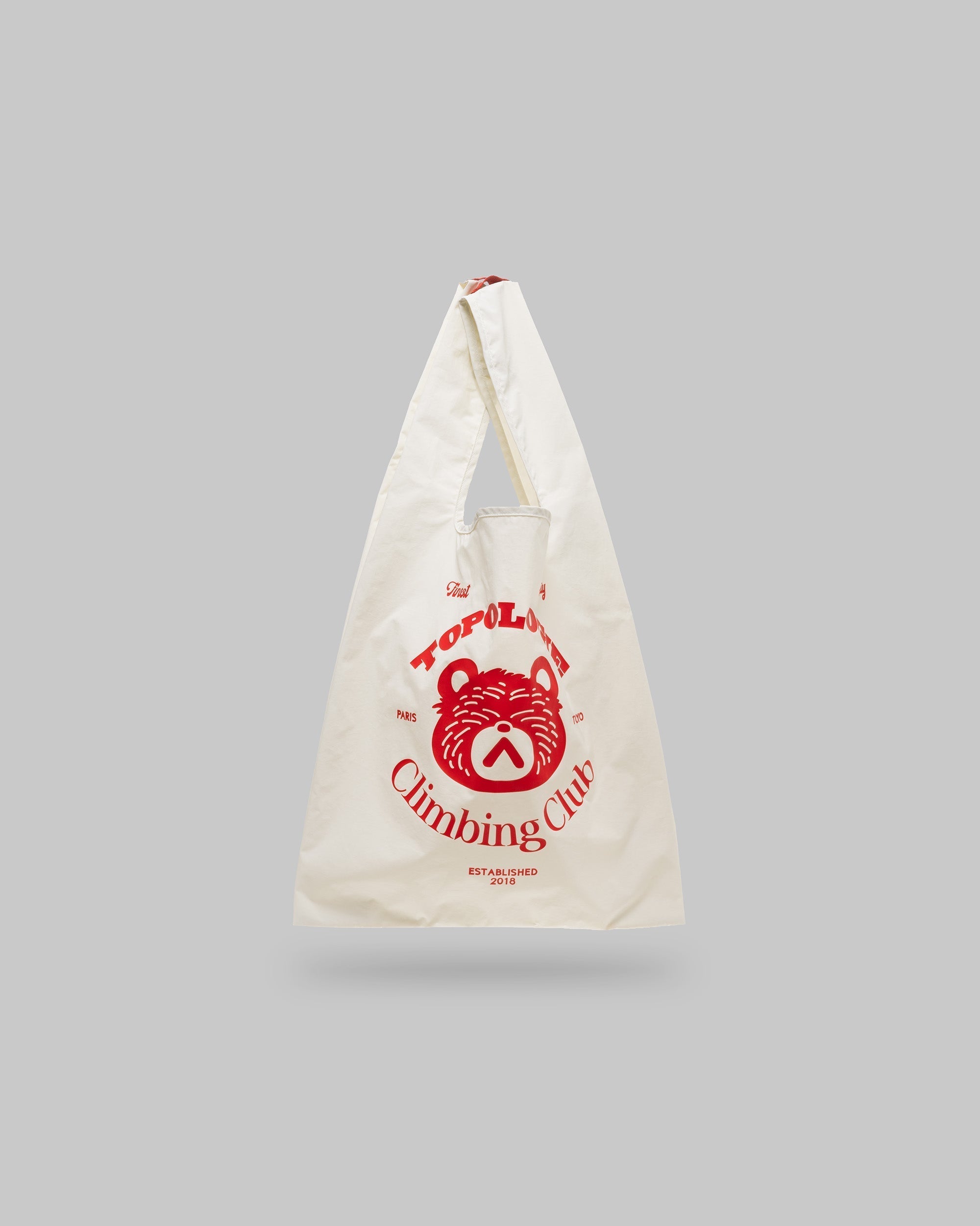 Konbini Bag Medium in off-white with a red bear graphic and Topologie Climbing Club text, shown against a light grey background.