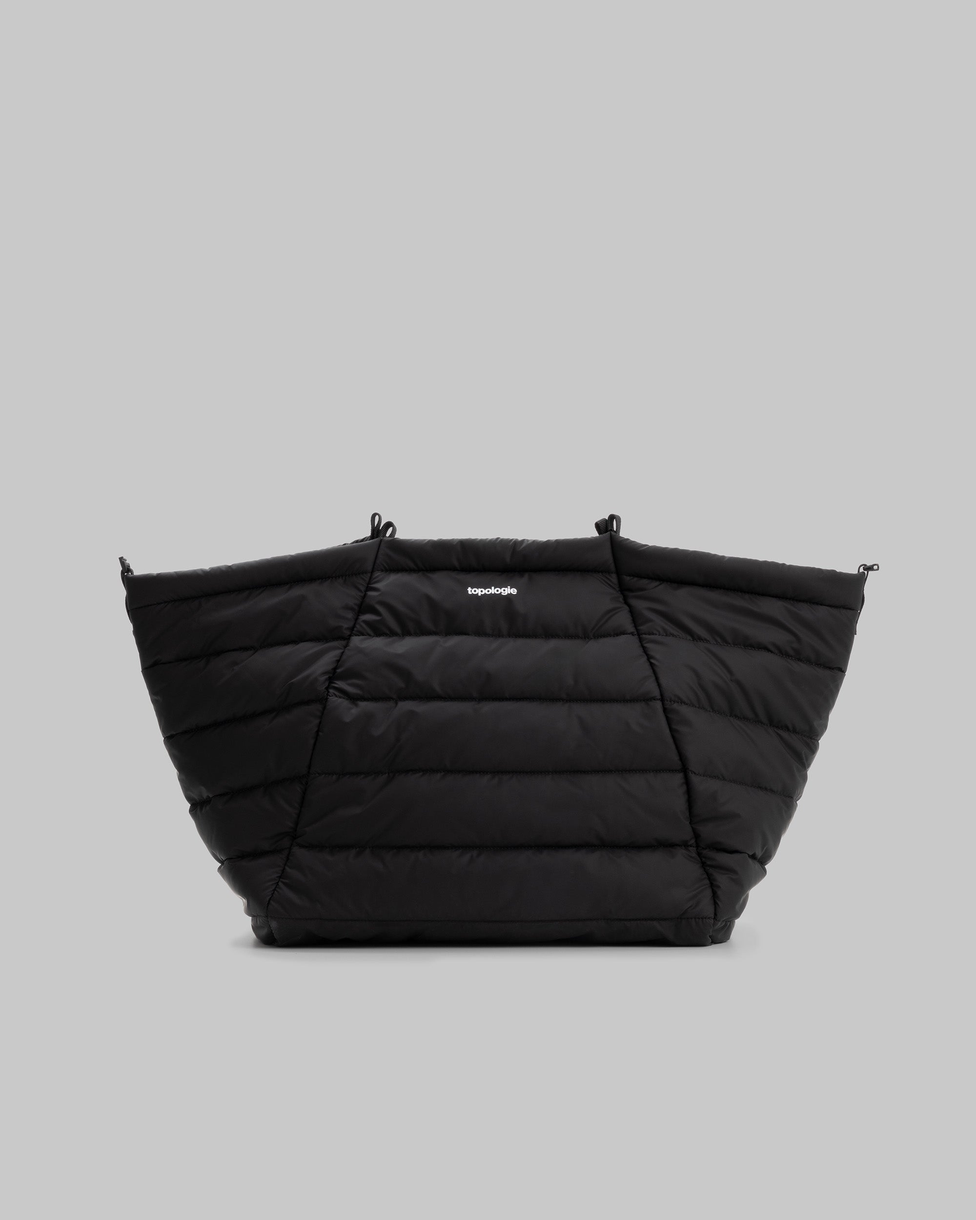 Marche Tote Large in black quilted fabric with a white topologie logo and attachment loops, shown against a light grey background.