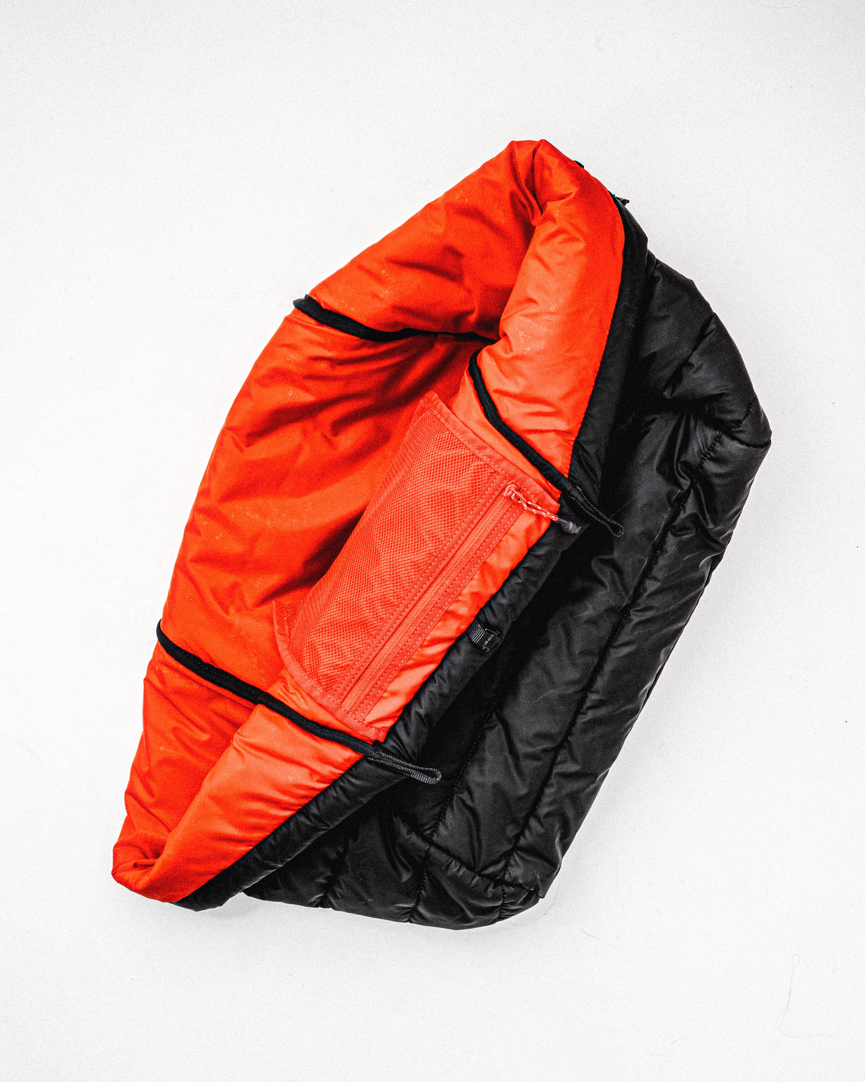 Marche Tote Large shown open to reveal its bright orange interior lining and a zippered mesh pocket against a black quilted exterior.