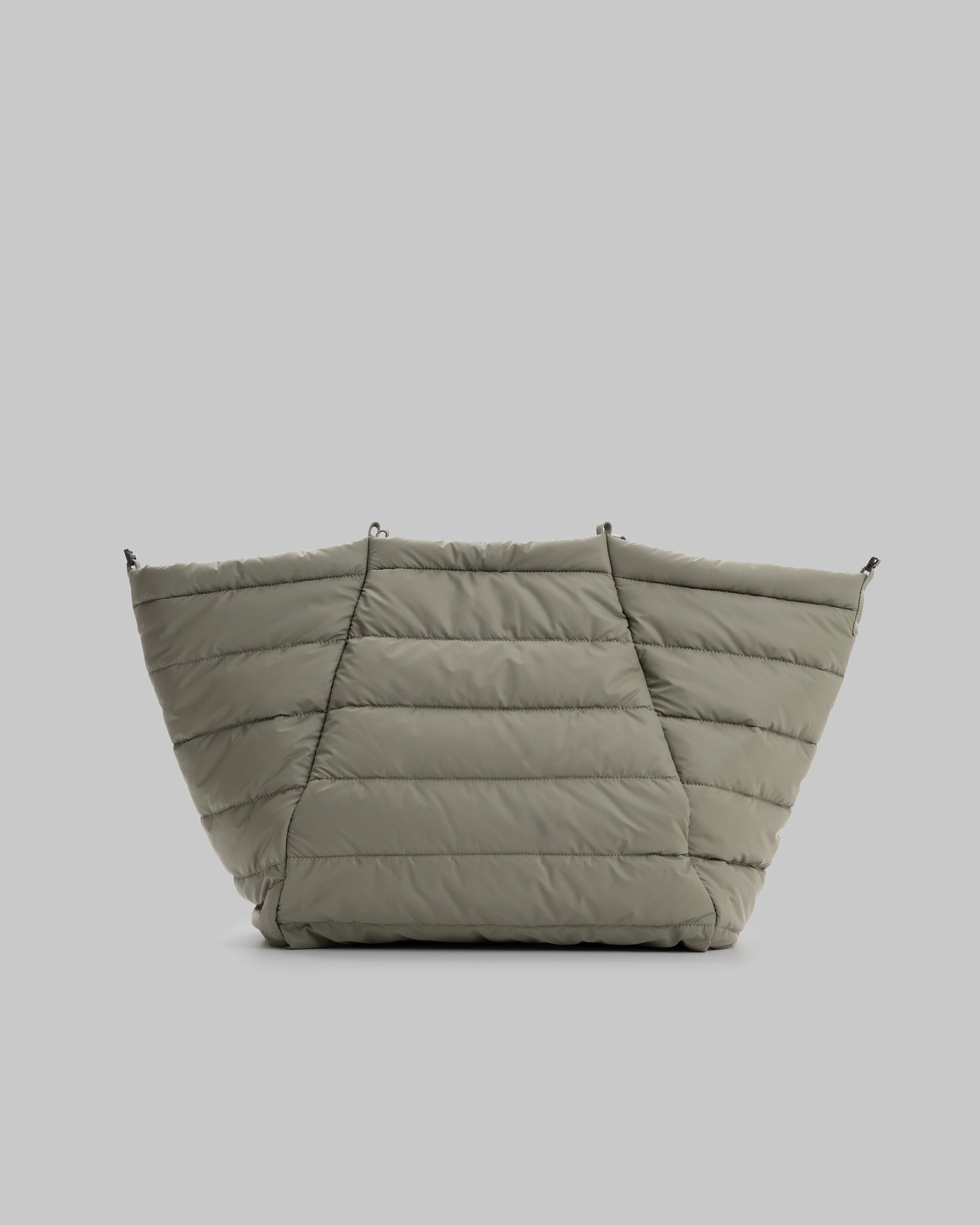 Marche Tote Large in moss green puffy needle ripstop with horizontal quilting and black hardware loops, shown against a light grey background.