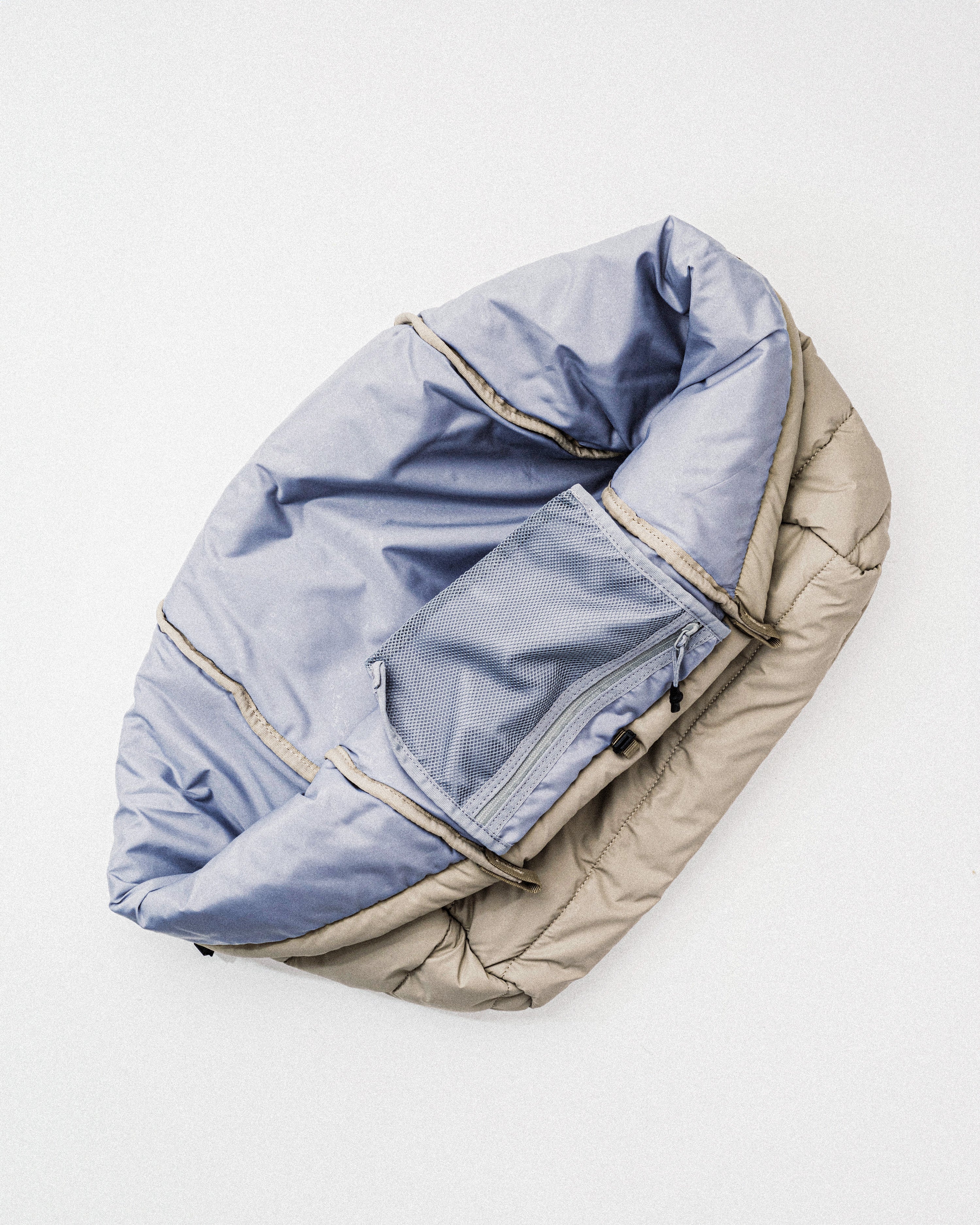 Marche Tote Large in taupe quilted fabric shown open with a light blue interior and mesh pocket on a grey background.