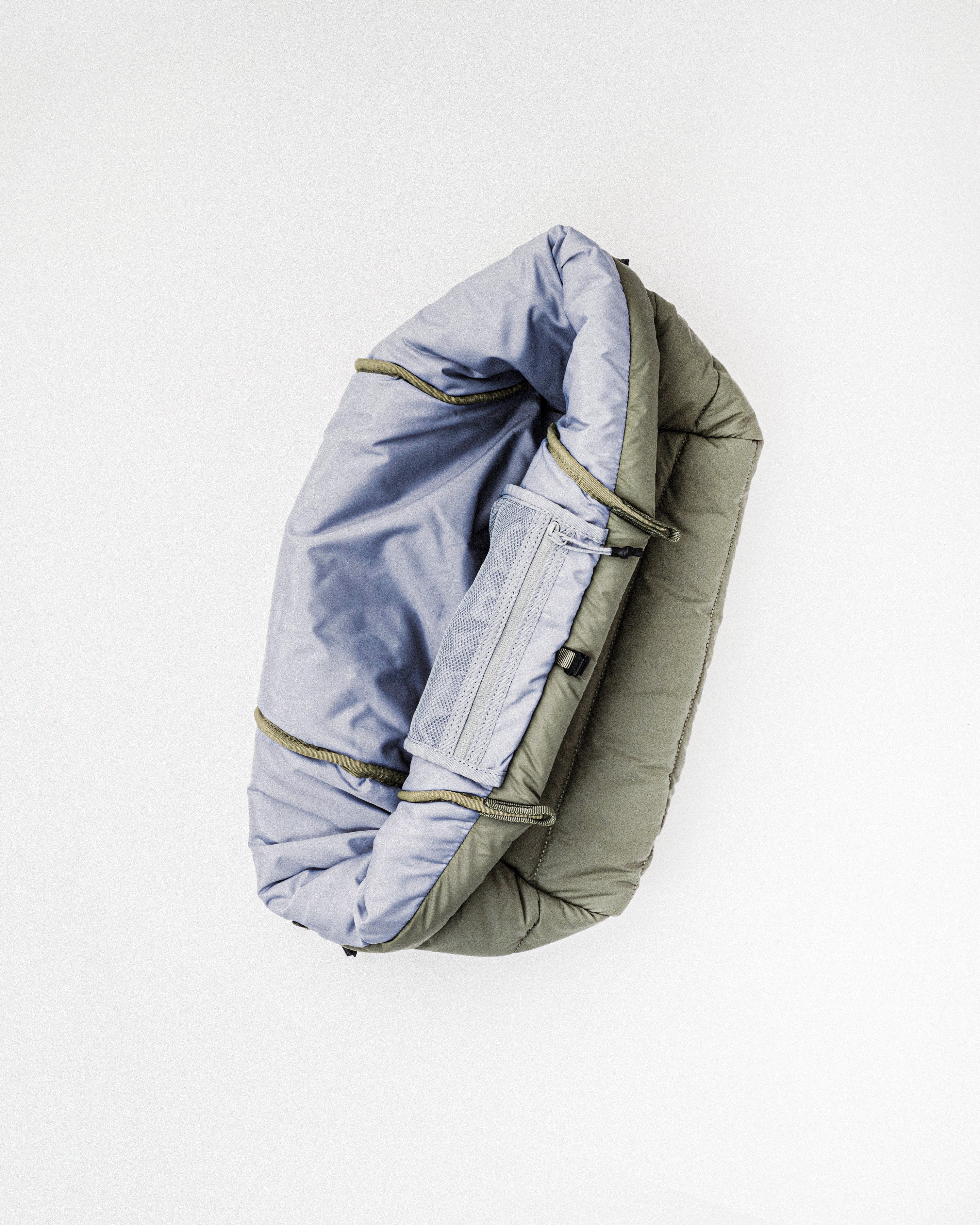 Marche Tote Medium shown open to reveal a light purple interior lining and a zippered mesh pocket against olive quilted exterior.