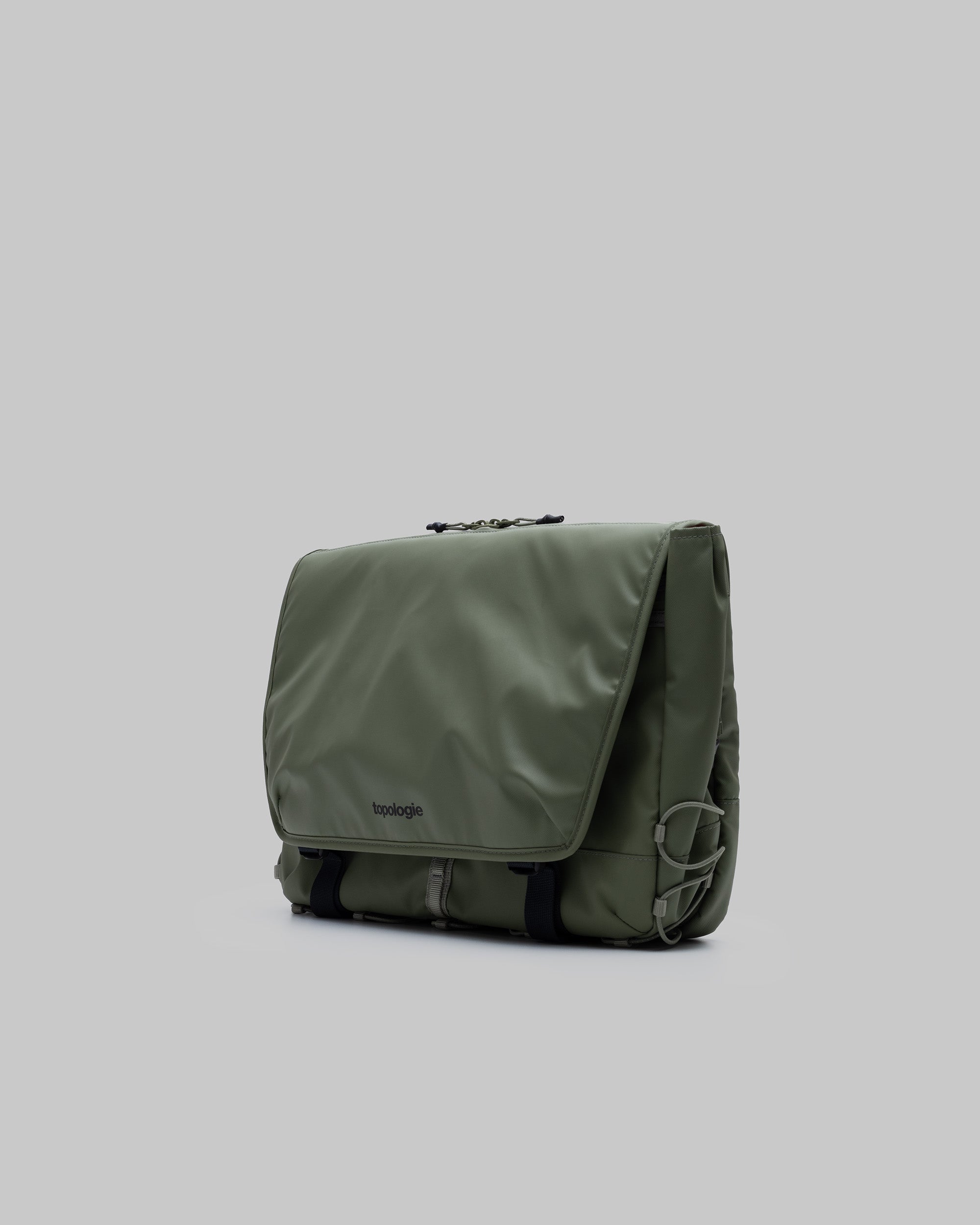 Messenger Sacoche Large in moss with black webbing straps, buckles, and a topologie logo, shown against a light grey background.