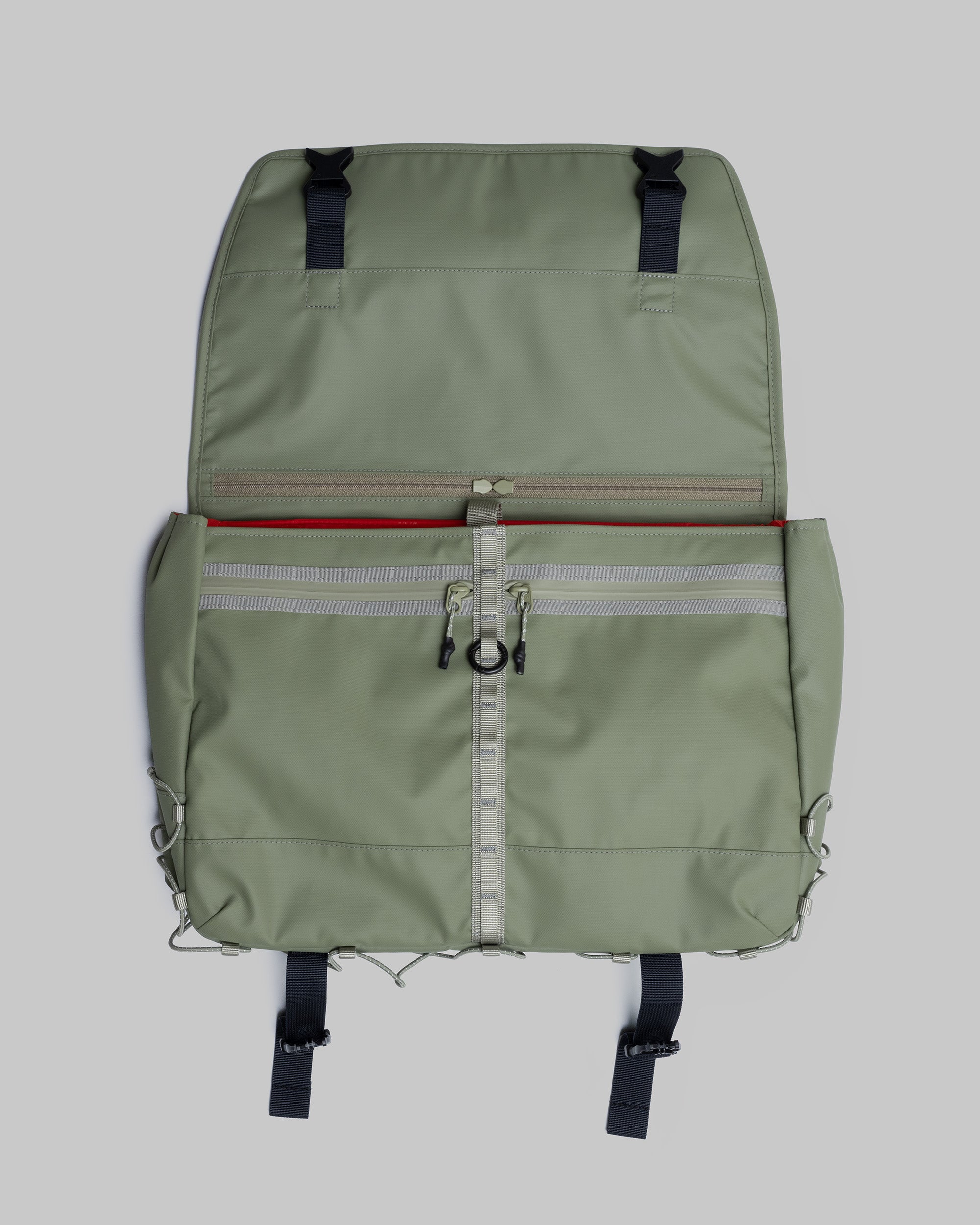 Messenger Sacoche Large in moss green with a red interior and webbing daisy chain, shown open against a light grey background.