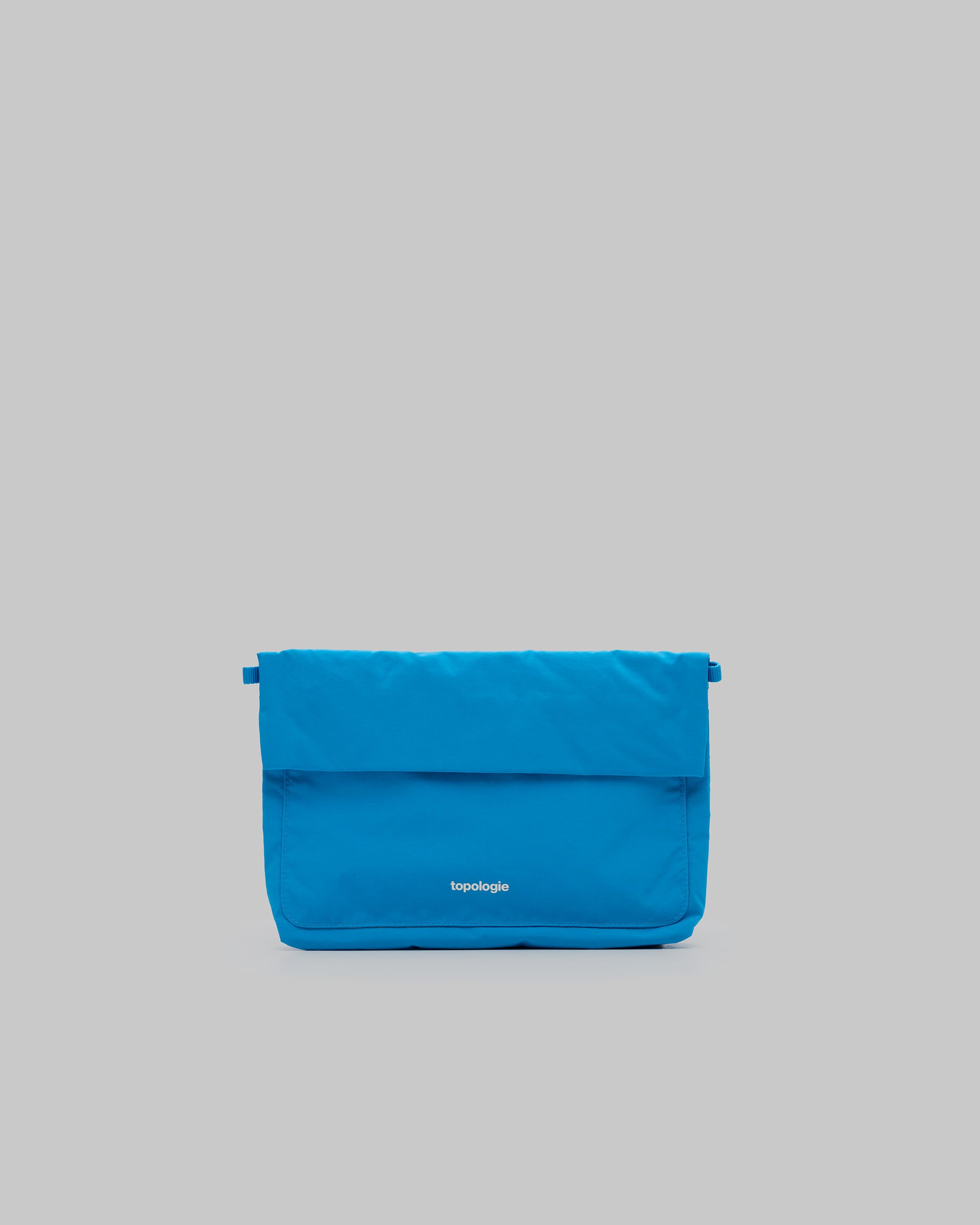 Musette Medium in atomic blue padded fabric with a white topologie logo, shown against a light grey background.