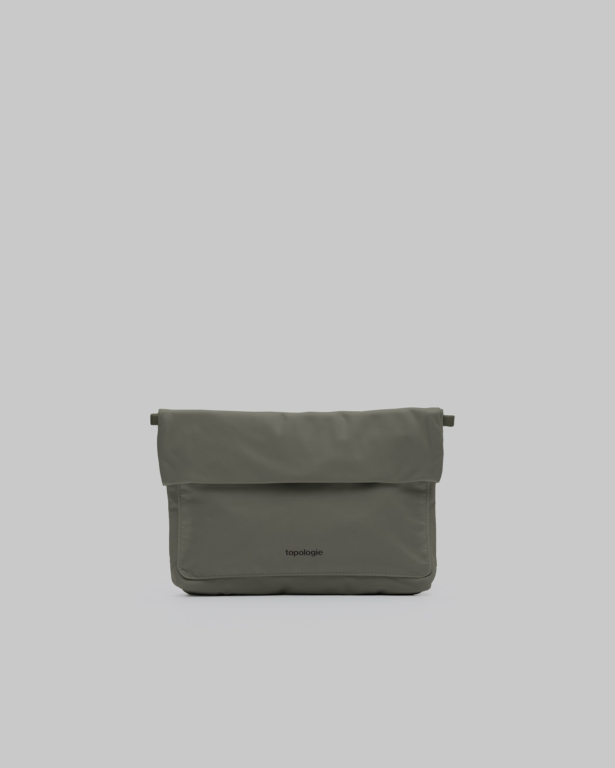 Musette Medium in moss with a fold-over flap and black topologie logo, shown against a light grey background.