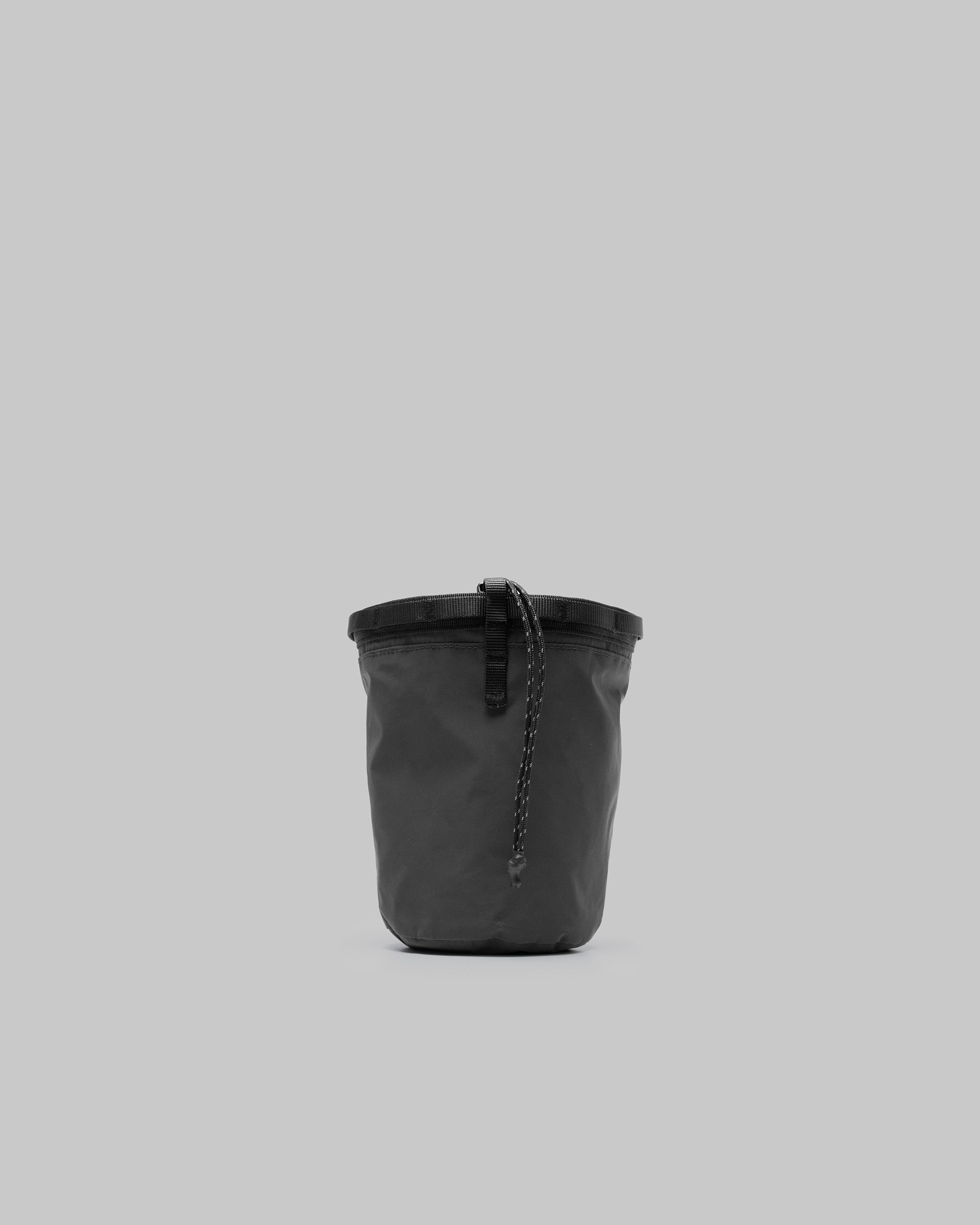 Chalk Bag in dark grey matte-coated fabric with black webbing trim and a speckled drawstring cord, shown against a light grey background.