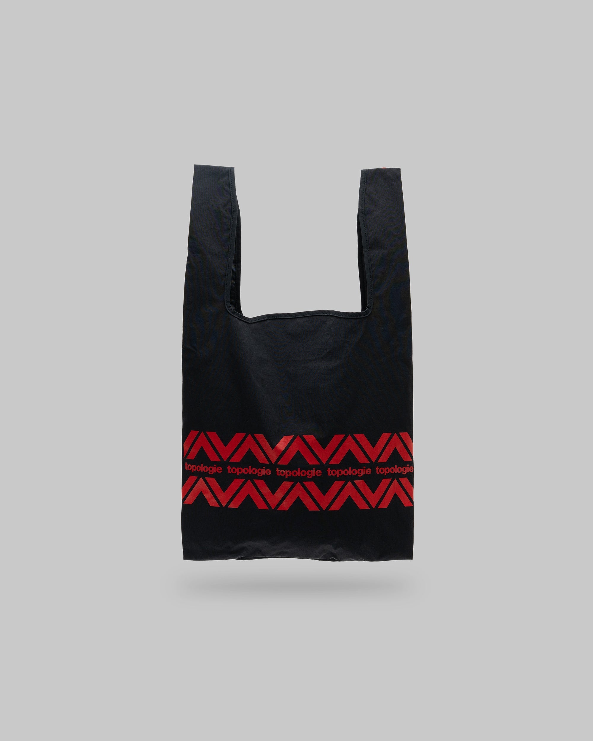 Konbini Bag Medium in black with red geometric chevron patterns and topologie text, shown against a light grey background.