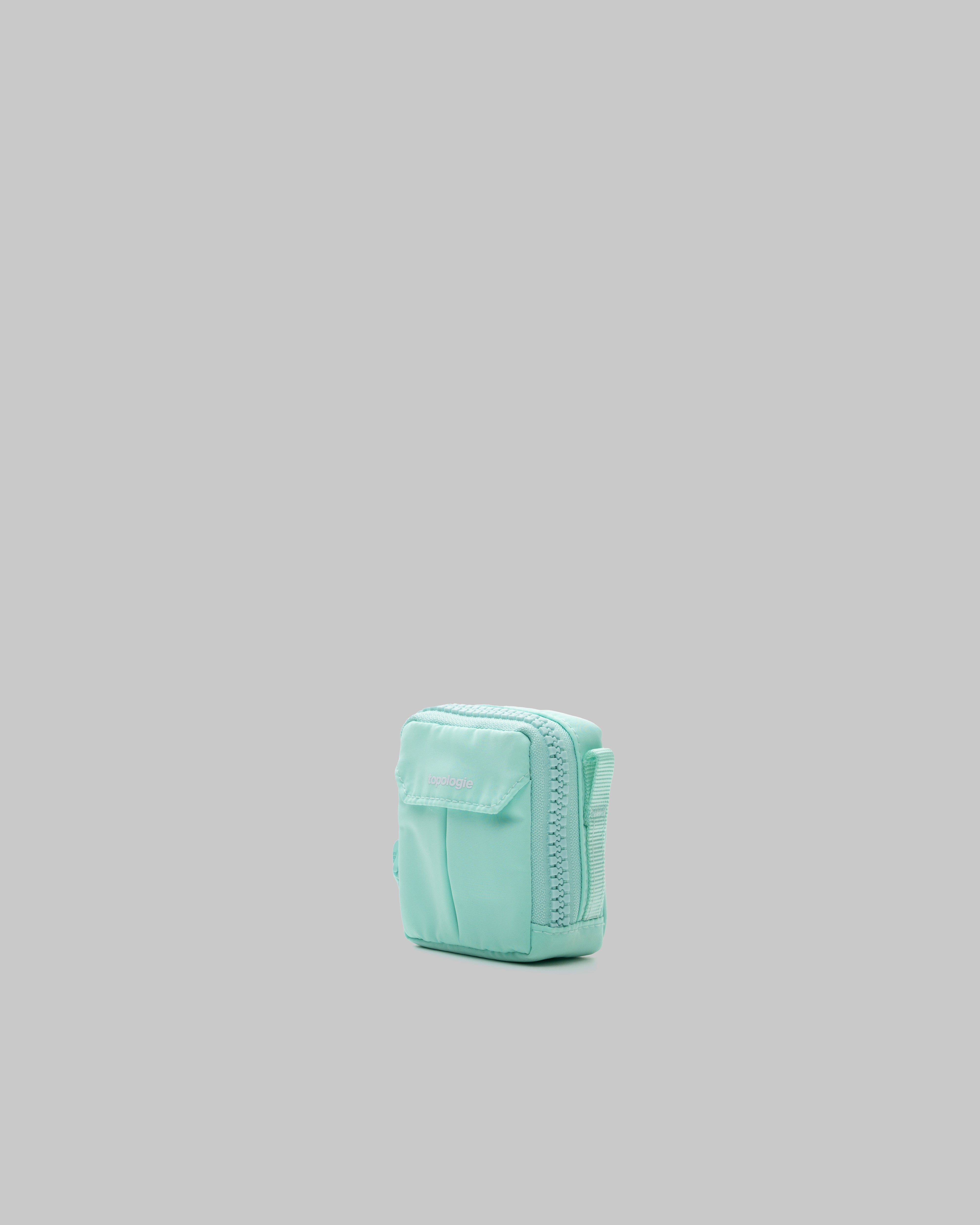 Mini Utility Sacoche in mint green with a front flap pocket and white topologie logo, shown against a light grey background.
