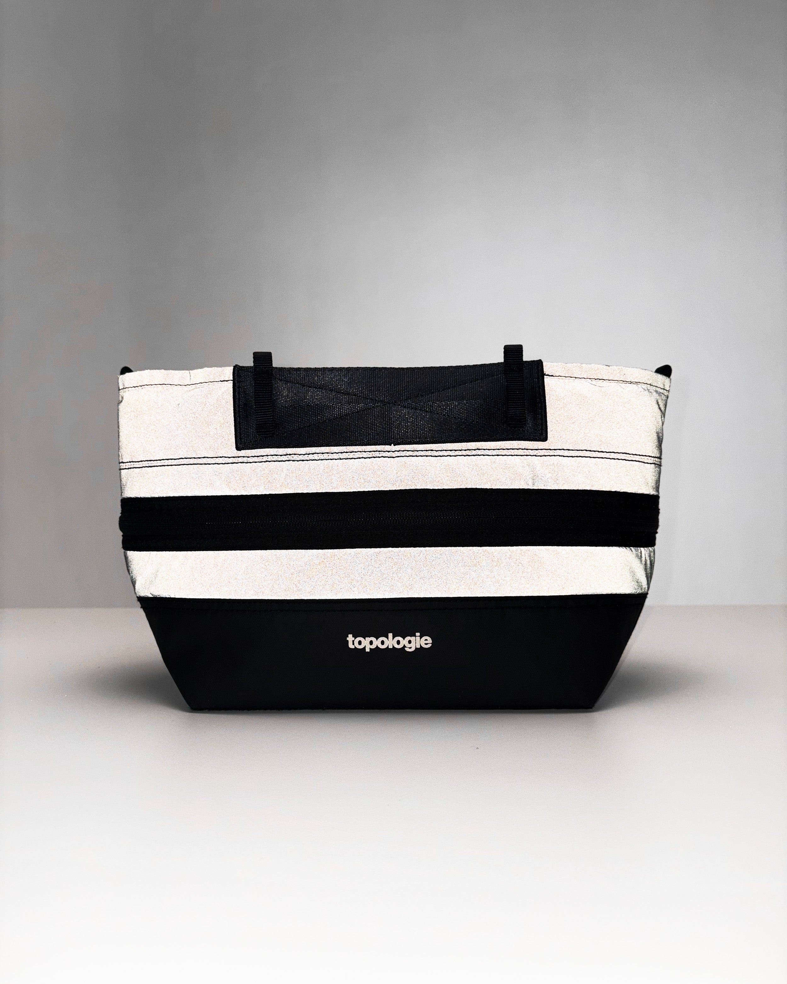 Convert Tool Bag in reflective silver and black with a mesh top panel and white topologie logo, shown against a light grey background.