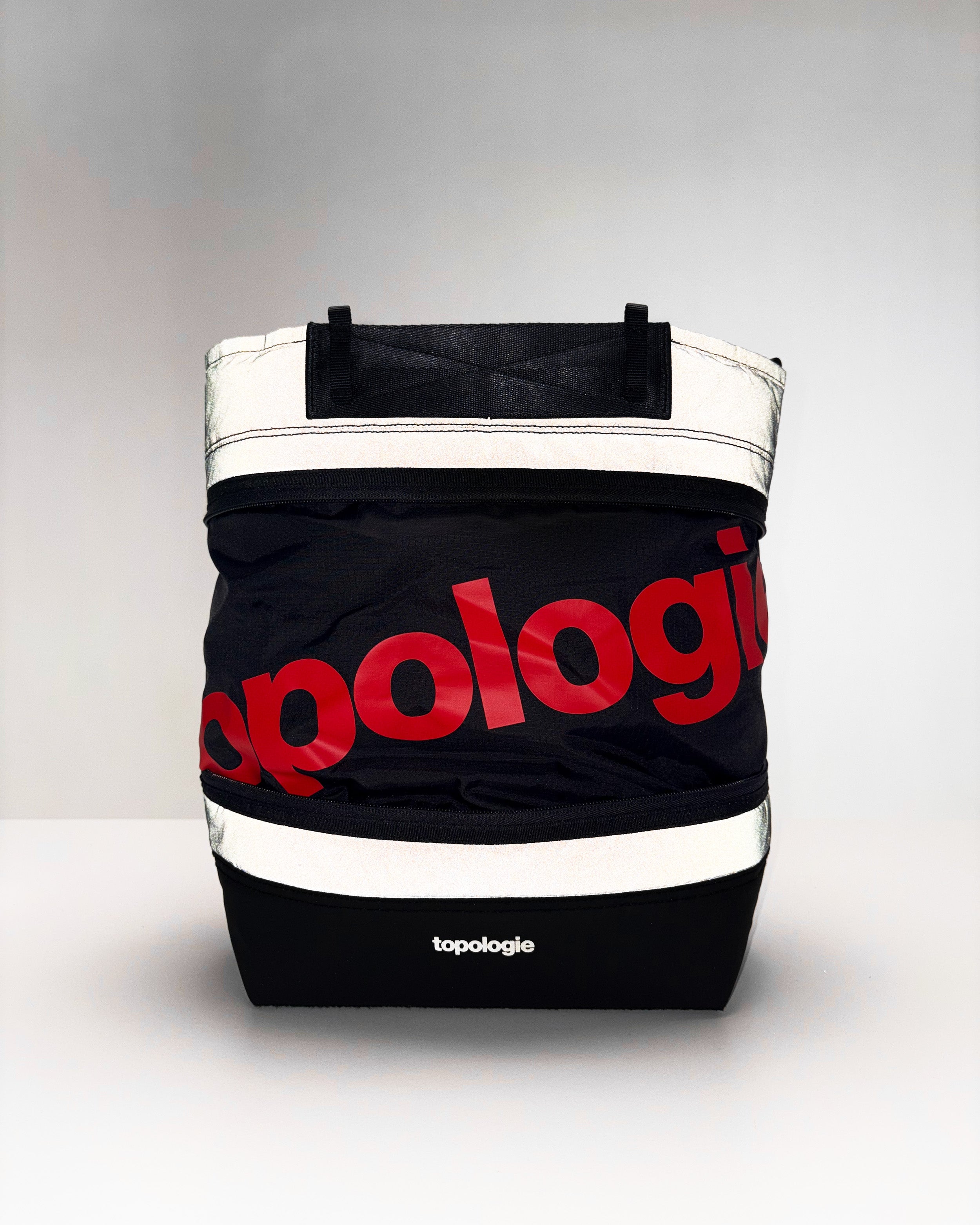 Convert Tool Bag in black with horizontal silver reflective bands and a large red topologie logo, shown against a light grey background.
